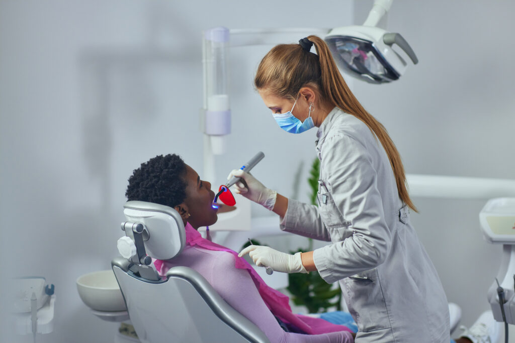 Dentist with face mask checking patient's teeth