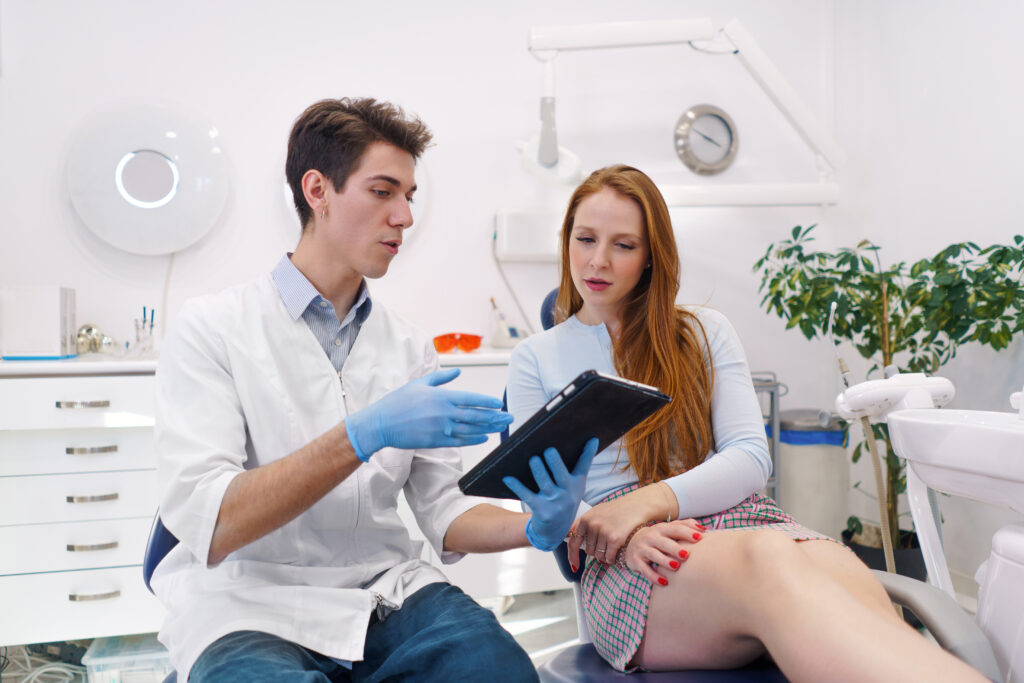 Male dentist showing tablet to female patient